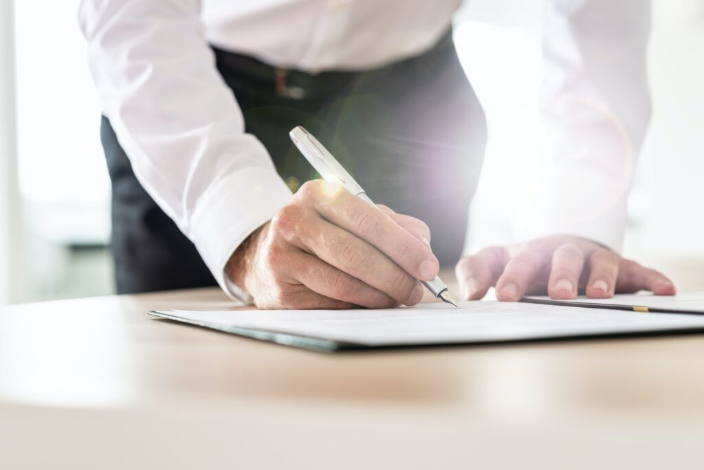 Unrecognizable businessman leaning in to sign a contract